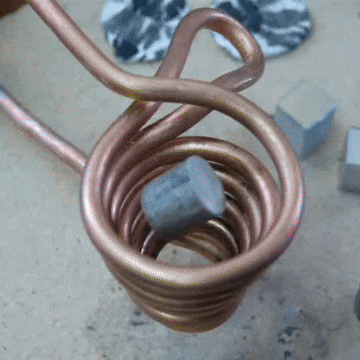 A gif of a small cylinder of aluminum levitated inside a copper induction coil; as the power increases, the floating aluminum melts into a white-hot teardrop shape; the operator pokes the molten aluminum with a pencil