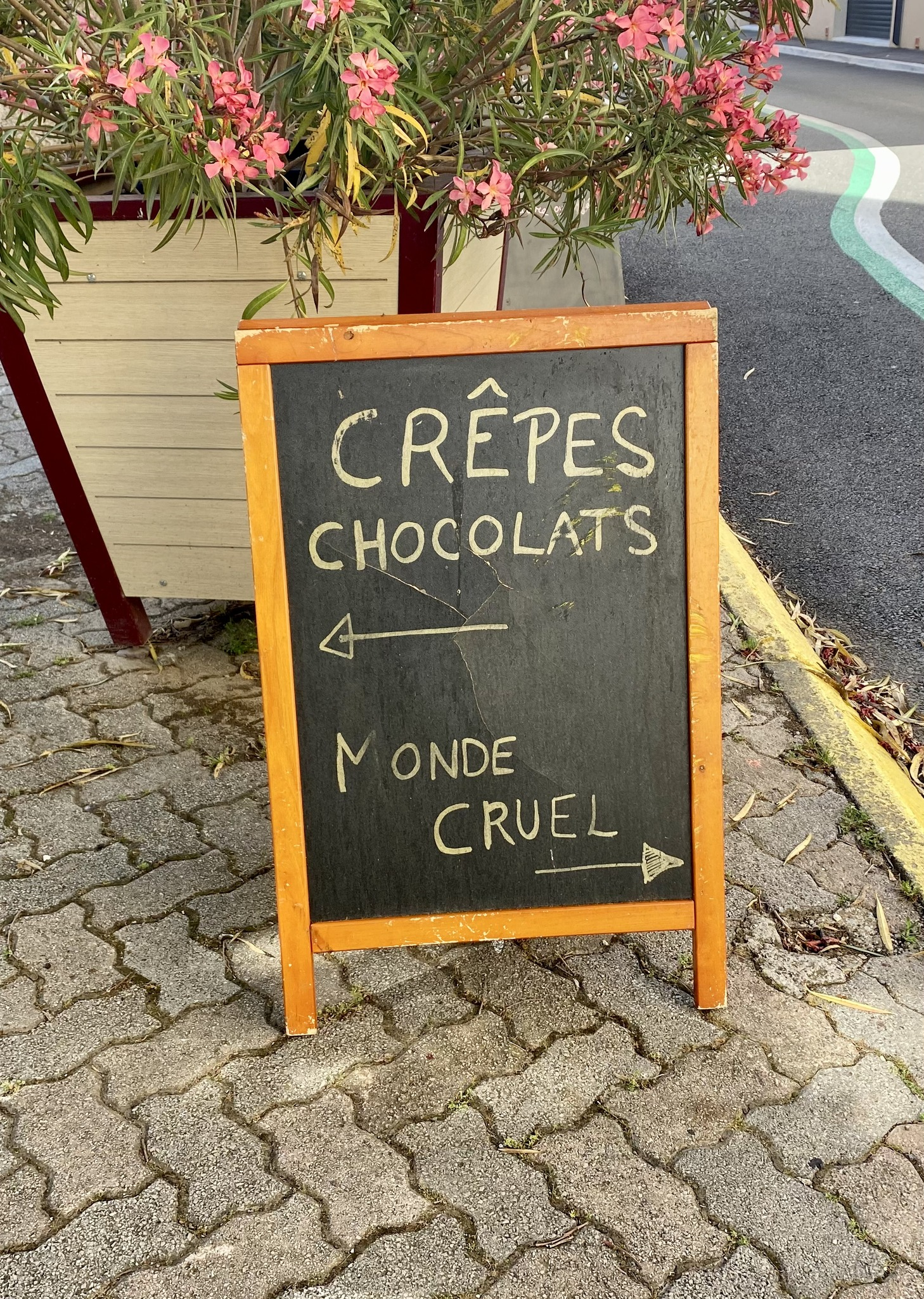 Photo d’une ardoise qui t’invite à faire un choix important dans ta vie : les crèpes au chocolat ou le monde cruel.