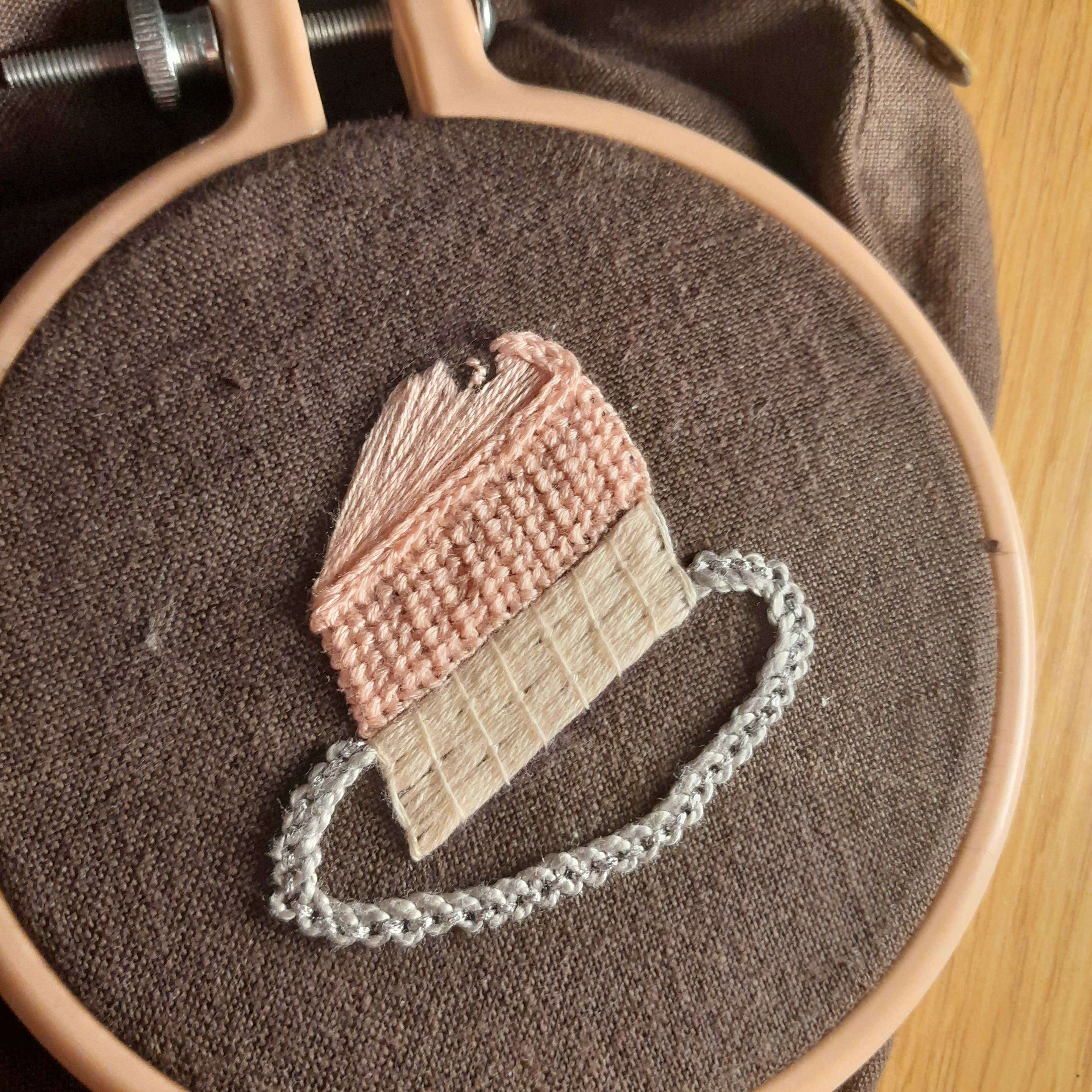 picture of an embroidery of a strawberry cake in progress. only some of the top is missing.