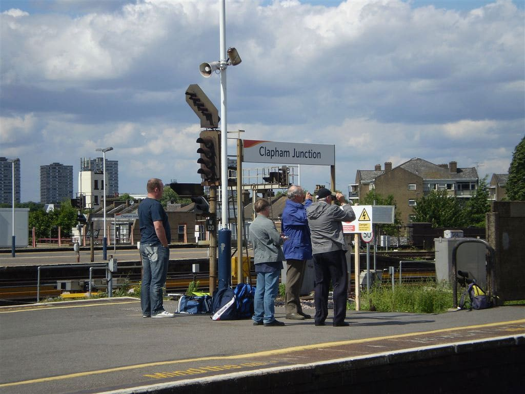 photographie de gens de dos sur un quai de gare attendant le passage d’un train